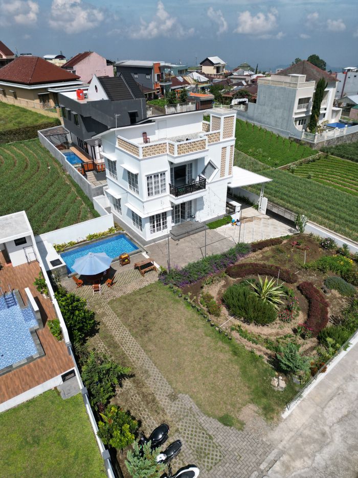 Aerial view of a modern villa with a garden and pool in a suburban area.