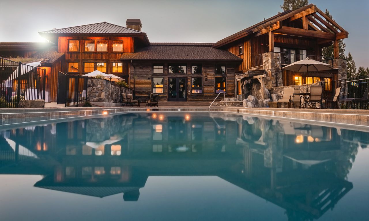 Home Stunning wooden villa with a large pool and cozy lights, perfect for a luxurious escape.